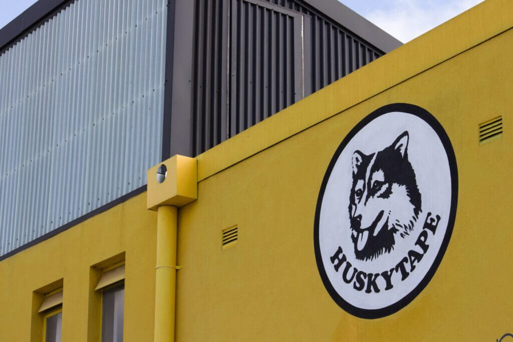 Location Husky Tape logo painted on a yellow factory building